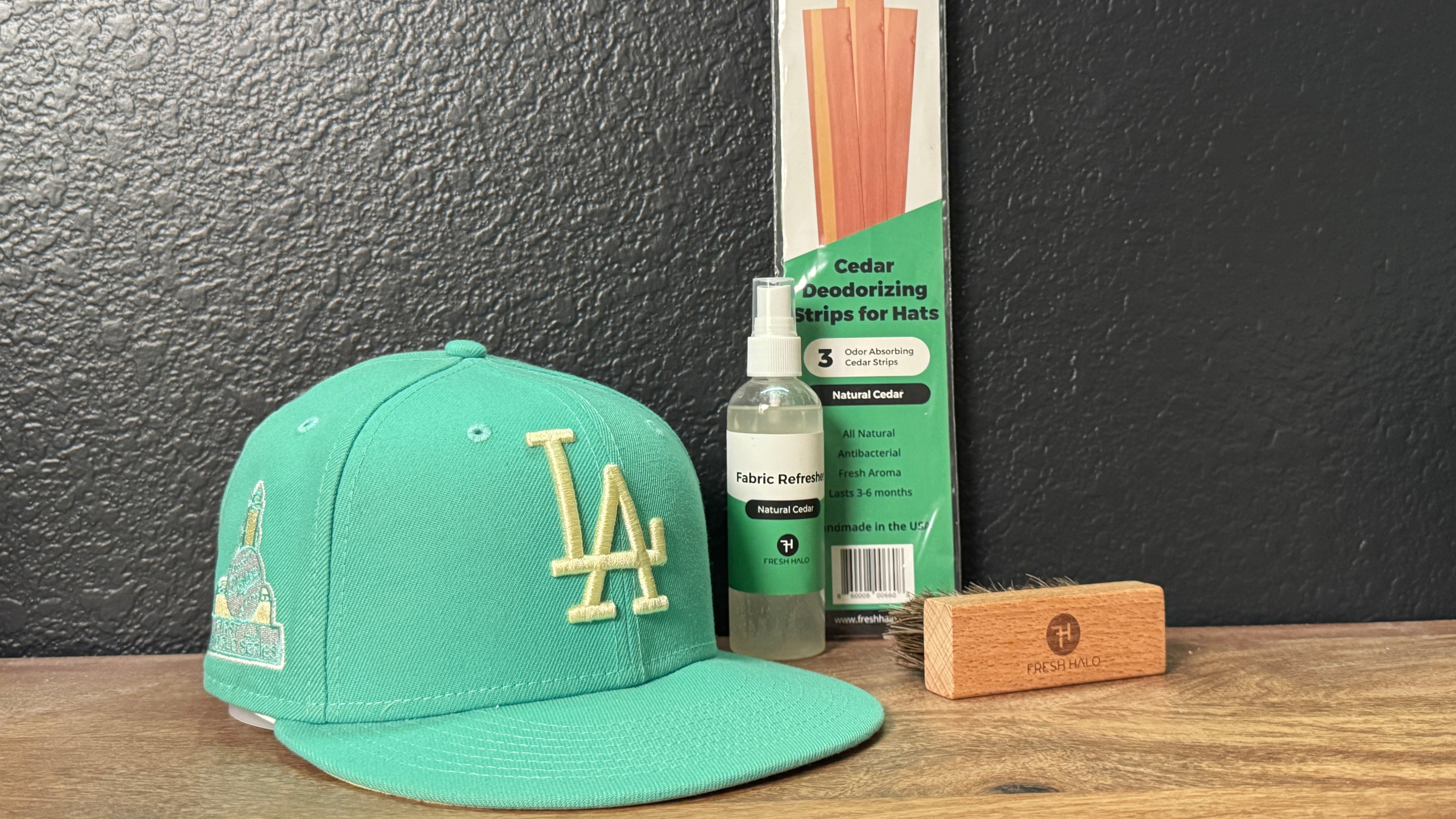 Green cap with gold logo, bottle, and packaging on a wooden surface against a dark wall.